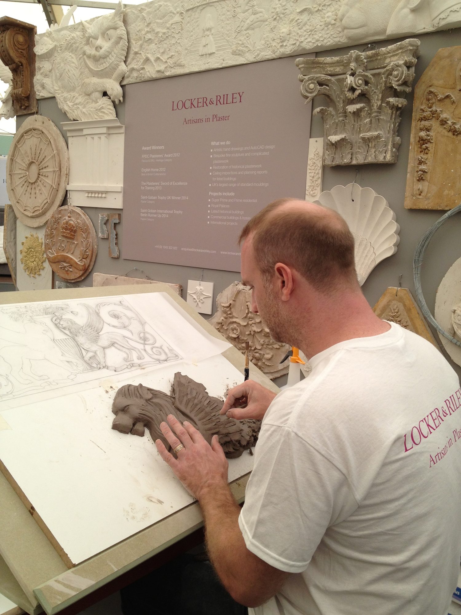 Intricate artistry……a beautiful rendering of a fanciful figure (seen upper right) as it is being carefully transformed by the artist into the clay model. Although there are many more stages before reaching the final piece… we can imagine the elegance this molding will add to the architecture…